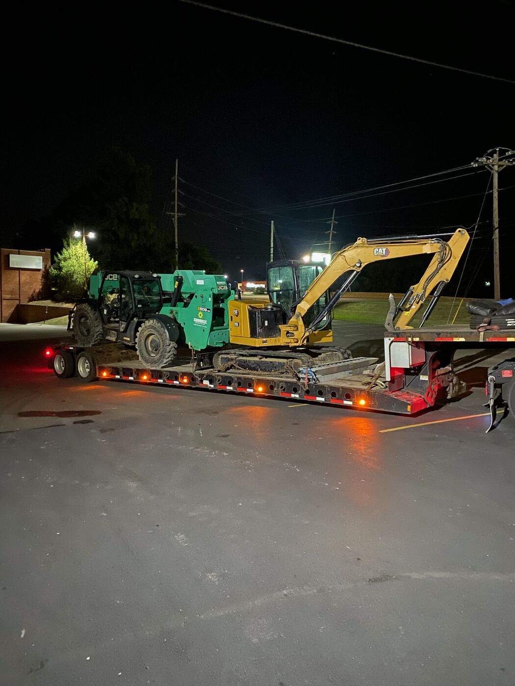 Equipment loaded on a lowboy trailer at night