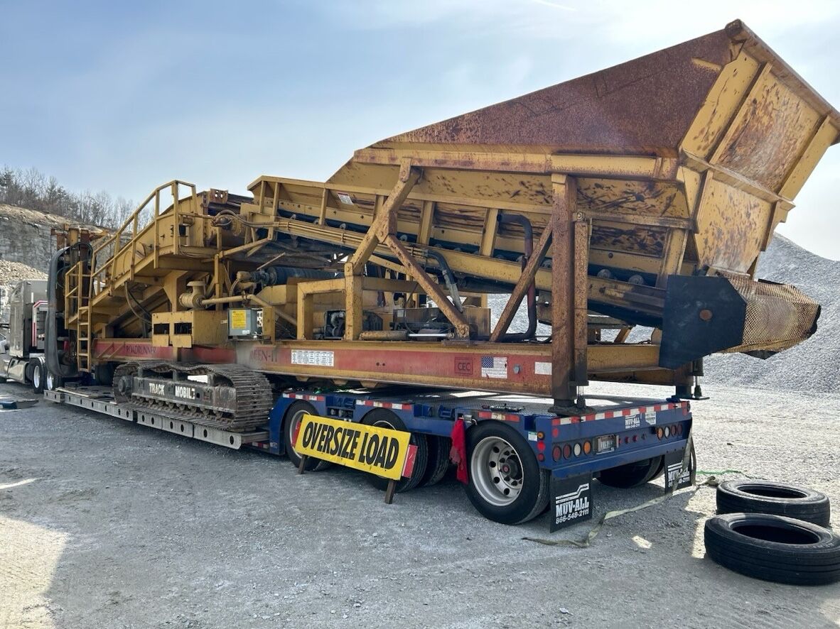 Mobile screening plant on a lowboy trailer with oversize load banner